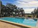 Sparkling community pool surrounded by lounge chairs, tables, and lush greenery on a sunny day at 1728 Golfview Dr # 1728, Tarpon Springs, FL 34689