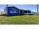 Back exterior of blue home, enclosed patio, and expansive green lawn at 3805 Baden Dr, Holiday, FL 34691