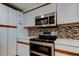 Close-up of updated stainless steel oven and microwave, along with a multi-colored tile backsplash at 3805 Baden Dr, Holiday, FL 34691