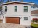 Two story home with a brown garage door, green grass, and pink flowers at 4809 W Juno St, Tampa, FL 33629