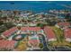 Aerial view of the community featuring red tiled roofs and a pool with ocean views in the distance at 538 Walden Ct, Dunedin, FL 34698