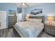 Comfortable bedroom featuring blue walls, grey furniture, beach art and neutral bedding and ceiling fan at 538 Walden Ct, Dunedin, FL 34698