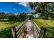 Exterior view of a lush lawn and a wooden bridge walkway with a tranquil setting at 538 Walden Ct, Dunedin, FL 34698