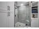 Modern glass enclosed shower with grey tiled walls, pebble floor and built in shelving at 538 Walden Ct, Dunedin, FL 34698