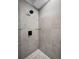 Grey tiled stand up shower with a black shower head, glass shelves, and pebble floor at 538 Walden Ct, Dunedin, FL 34698