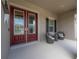 Close-up of a red double door with glass panels and a view of seating on the covered front porch at 6915 Sea Stone Ct, Apollo Beach, FL 33572