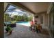 Covered patio with a pool, a wooden dining table, outdoor furniture, and a mounted television at 6915 Sea Stone Ct, Apollo Beach, FL 33572