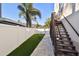 Exterior view of a fenced-in backyard and wood stairs leading to a balcony above at 100 Driftwood W Dr, Palm Harbor, FL 34683