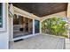A covered balcony with tile flooring overlooks the serene outdoor space visible through sliding glass doors at 100 Driftwood W Dr, Palm Harbor, FL 34683