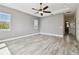 Bright bedroom with tray ceiling, fan, wood-look tile, and windows with shutters at 100 Driftwood W Dr, Palm Harbor, FL 34683