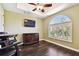 This game room has wood floors, a ceiling fan, an arched window, and a flat screen tv at 100 Driftwood W Dr, Palm Harbor, FL 34683
