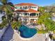 Aerial view of an expansive backyard with a freeform pool, lush landscaping, and balcony overlooking the water at 100 Driftwood W Dr, Palm Harbor, FL 34683