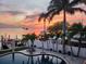 Panoramic sunset view with a pool, palm trees, and private boat dock on tranquil waterfront property at 100 Driftwood W Dr, Palm Harbor, FL 34683