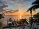Waterfront property overlooking the sunset with a wood dock and surrounding tropical plants at 100 Driftwood W Dr, Palm Harbor, FL 34683
