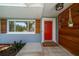 Inviting front entry featuring a bright red door, modern wood paneling, and manicured landscaping at 1220 Parkview Ln, Largo, FL 33770