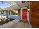 Inviting front entry featuring a bright red door, modern wood paneling, and colorful landscaping at 1220 Parkview Ln, Largo, FL 33770