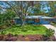 Charming single-story home featuring a lush front lawn, colorful landscaping, and a beautiful shade tree at 1220 Parkview Ln, Largo, FL 33770