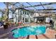 Backyard with a screened-in pool and patio area, including outdoor seating, dining, and grill at 14910 Northwood Village Ln, Tampa, FL 33613