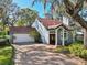 Charming home featuring a brick driveway, attached garage, and an arched entryway with white columns at 14910 Northwood Village Ln, Tampa, FL 33613