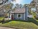 Charming light blue home with an arched window, covered porch, mature landscaping, and a brick driveway at 14910 Northwood Village Ln, Tampa, FL 33613