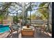 Screened-in pool area with lounge chairs and dining table, surrounded by lush landscaping and privacy fence at 14910 Northwood Village Ln, Tampa, FL 33613
