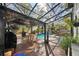 Screened-in pool with a covered patio, dining table, outdoor fan, lush landscaping, and ample seating at 14910 Northwood Village Ln, Tampa, FL 33613