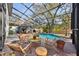 Screened-in pool area with lounge chairs and dining table, complete with grill and covered patio space at 14910 Northwood Village Ln, Tampa, FL 33613