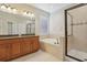 Well-lit bathroom featuring double vanity, soaking tub, glass-enclosed shower, and neutral tile for a spa-like feel at 1503 Yale Castle Ct, Ruskin, FL 33570