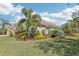 Beautifully landscaped front yard with lush green grass, colorful flowers and plants, and mature palm trees at 1503 Yale Castle Ct, Ruskin, FL 33570