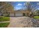 Long brick paver driveway leading to a three-car garage with mature landscaping and a manicured lawn at 17807 Crystal Cove Pl, Lutz, FL 33548
