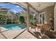 Enclosed pool area with screened ceiling, brick patio, lush landscaping, and outdoor seating at 17807 Crystal Cove Pl, Lutz, FL 33548