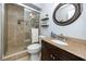 Well-appointed bathroom featuring granite vanity, framed round mirror, and a tiled walk-in shower with glass door at 1824 Clearbrooke Dr, Clearwater, FL 33760
