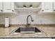 A kitchen sink has a modern faucet and neutral colored counters and subway tile backsplash with floating shelves above at 2042 Australia W Way # 6, Clearwater, FL 33763