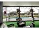 View of the pool through the screened enclosure with trees adorned with pink flowers and green carpeting at 2233 Golf Manor Blvd, Valrico, FL 33596