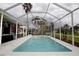 A view of an in-ground swimming pool with spa and screened enclosure surrounded by landscaping at 2233 Golf Manor Blvd, Valrico, FL 33596