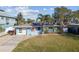 Home exterior featuring solar panels, a one car garage, a palm tree, and well-manicured lawn at 2451 Baywood W Dr, Dunedin, FL 34698