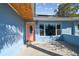 Charming home exterior showcasing a light blue facade, a colorful front door and a spacious front patio at 2451 Baywood W Dr, Dunedin, FL 34698