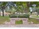 A welcoming entrance to John R. Lawrence Pioneer Park, featuring lush greenery and a charming brick sign at 2451 Baywood W Dr, Dunedin, FL 34698