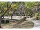 View of the brick house situated behind a white fenced bridge; tree coverage surrounds the house at 2906 Pemberton Creek Dr, Seffner, FL 33584