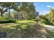 View of the brick home with mature trees and a grassy lawn, beside a scenic water feature at 2906 Pemberton Creek Dr, Seffner, FL 33584