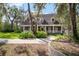 Beautiful brick home with front porch and dormer windows surrounded by mature trees, lush greenery, and blue sky at 2906 Pemberton Creek Dr, Seffner, FL 33584