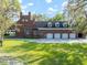 Back of brick home featuring a four-car garage, well-manicured lawn, and mature trees at 2906 Pemberton Creek Dr, Seffner, FL 33584