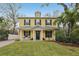 Inviting yellow two-story home with a covered front porch and well-manicured lawn and lovely tropical foliage at 2915 W Bay View Ave, Tampa, FL 33611