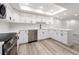 Modern kitchen with white cabinets, stainless steel appliances, quartz countertops, and wood-look flooring at 3021 Countryside Blvd # 23A, Clearwater, FL 33761