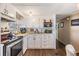 Well-lit kitchen featuring white cabinetry, stainless steel appliances and wood-look flooring at 37246 Eileen Ave, Zephyrhills, FL 33542