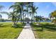 Lush backyard featuring a stone path leading to the lake, palm trees, and an outdoor seating area for relaxation at 3749 Zachary St, New Port Richey, FL 34655