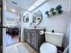 Well-lit bathroom features a gray vanity with a round mirror and modern fixtures at 513 Hammock Pine Blvd, Clearwater, FL 33761