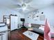 Cozy bedroom features dark wood floors, a ceiling fan, and a comfortable gray futon with pink and white pillows at 513 Hammock Pine Blvd, Clearwater, FL 33761
