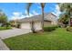 Side view of a home with a well-manicured lawn, mature trees, lush landscaping and a three-car garage at 5703 Tanagerside Rd, Lithia, FL 33547