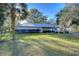 Single-story home with metal roof and a well-maintained, lush green lawn at 8249 Cindy Dr, Zephyrhills, FL 33540